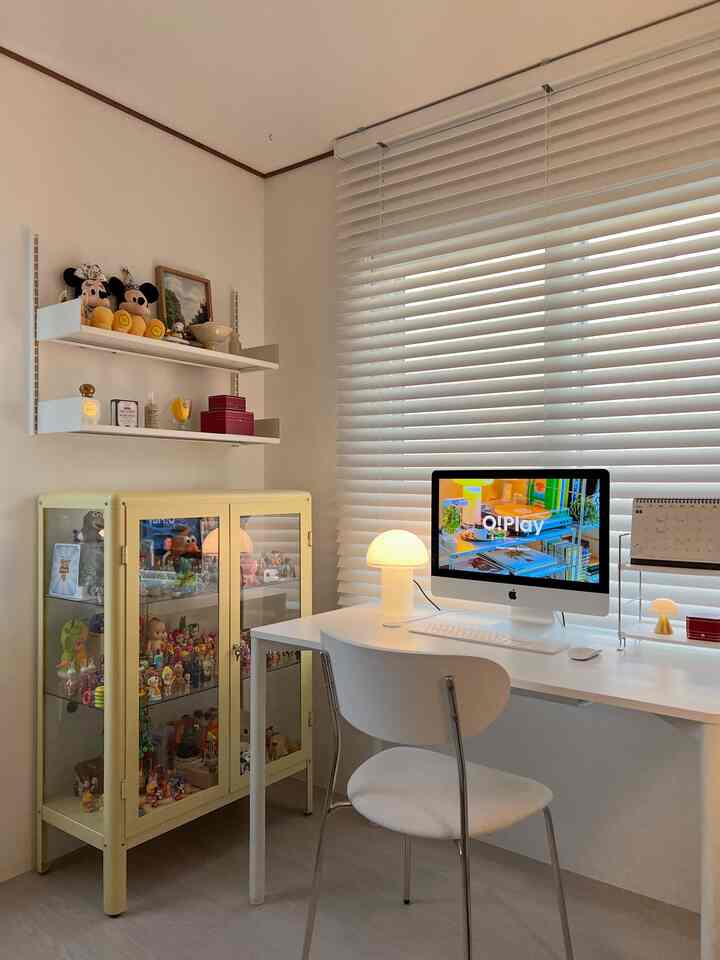 A compact home office in white and beige tones featuring a desk, computer, and storage cabinet in a clean setting