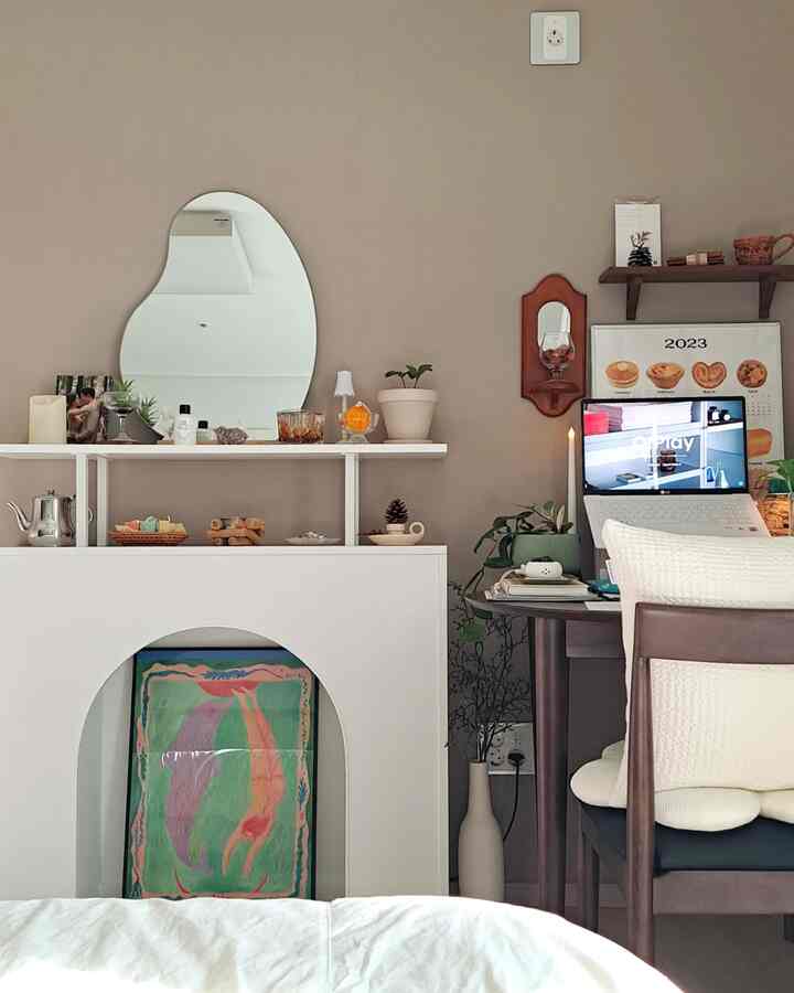ベージュ色の壁と白いベッド、デスク、植物が配置された落ち着いた寝室のインテリア