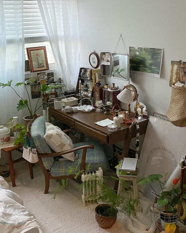 白と茶色のトーンが特徴の寝室にある木製のデスク、クッション、多彩なオブジェが配置された落ち着いたナチュラルモダンな空間