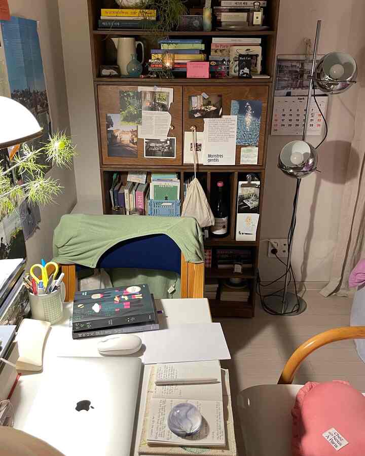 A white-toned home office featuring wood-tone furniture with desk and bookshelf, creating a cozy remote work environment