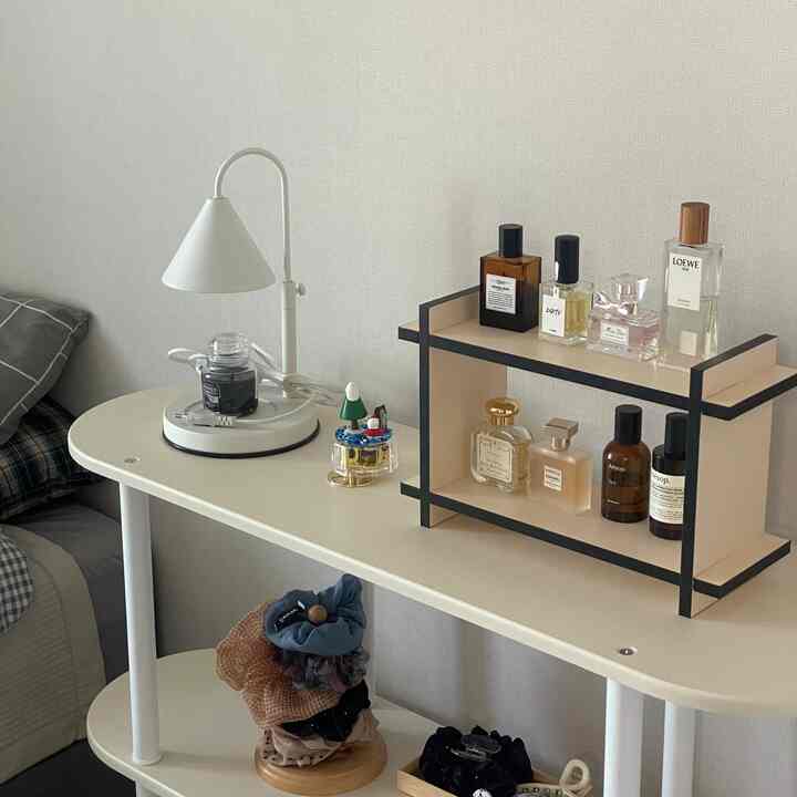 White and beige toned bedroom featuring a modern shelf with perfumes and candles arranged in a cozy setting