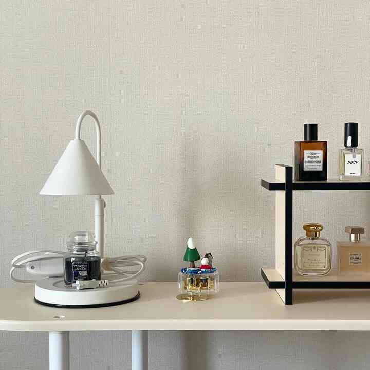 Natural-toned bedroom shelf featuring a table lamp, music box, and perfume bottles creating a cozy atmosphere