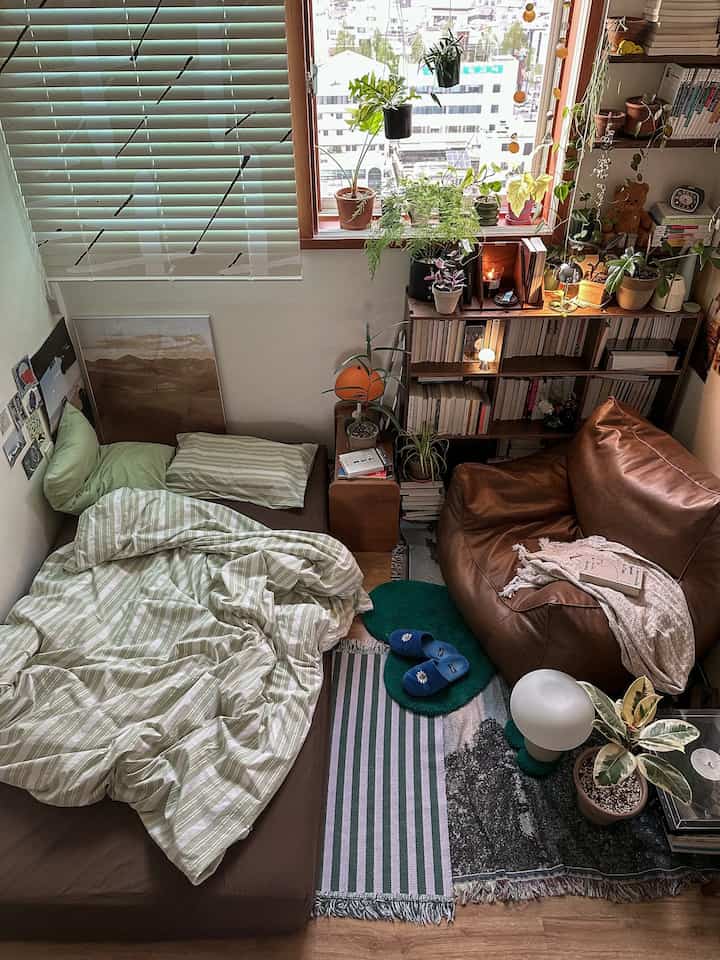 Natural color and wood tones in a compact bedroom featuring a bean bag sofa and diverse plants creating a cozy plant interior style