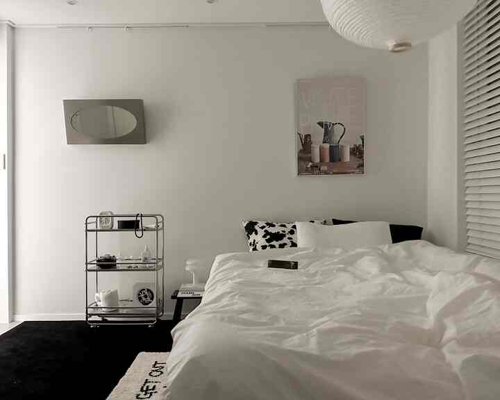 ホワイトとブラック、シルバーのトーンの寝室、清潔なベッドとトロリーが配置されたモダンでシンプルなインテリア