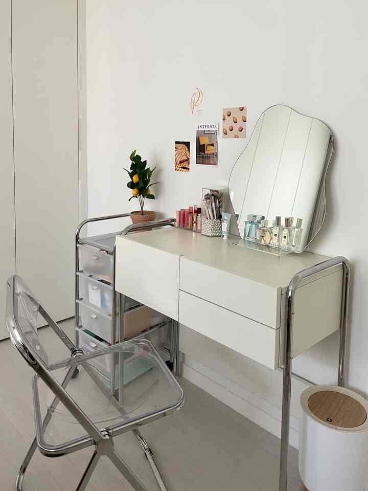 白い壁とシンプルな化粧台、透明なアクリルチェアが配置された清潔感のある空間