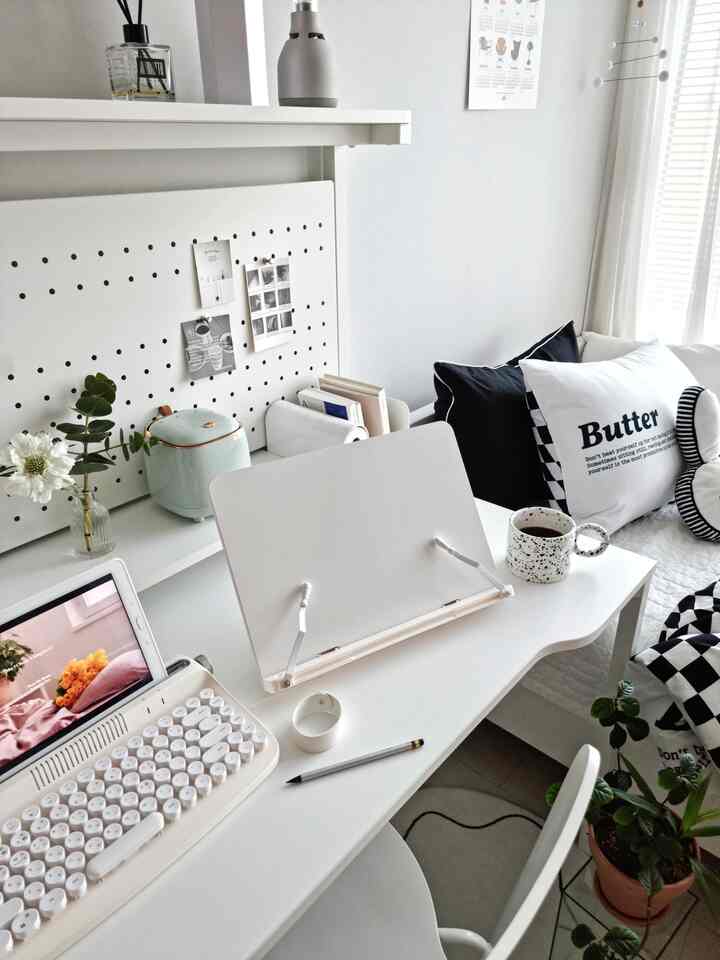 Compact white-toned home office space featuring a simple desk with a bookstand, tablet, and office chair in a neat setup