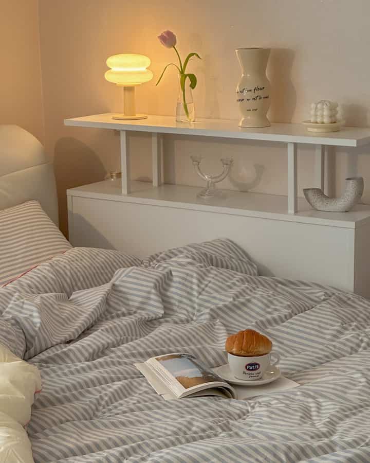 Warm white and natural-toned bedroom featuring striped duvet cover and decorative objets, creating a cozy atmosphere