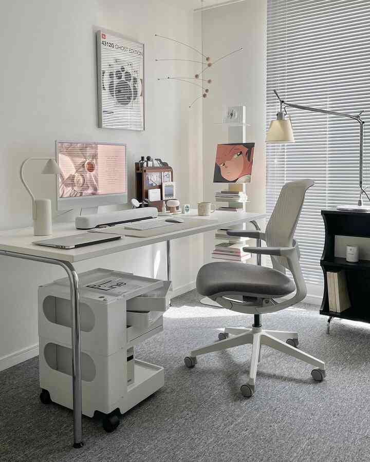 White and gray toned home office space featuring a computer desk and ergonomic chair with modern clean design