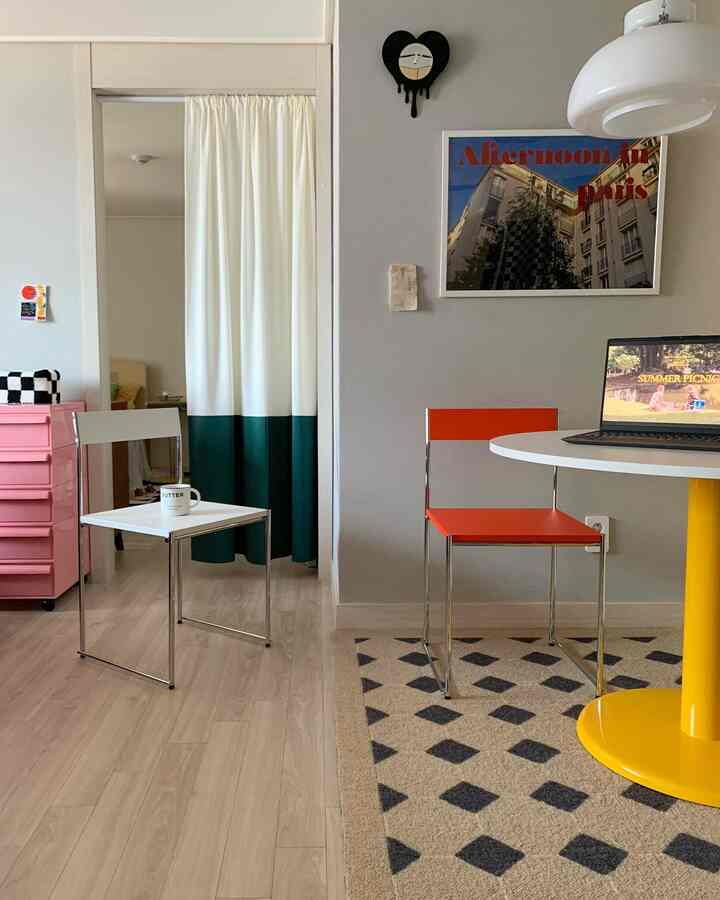 白を基調としたリビングとキッチンの空間に、シンプルモダンな椅子と黄色のアクセントテーブルが配置された雰囲気のあるインテリア