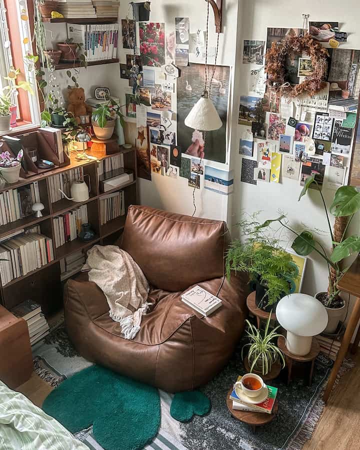 Natural tone small room featuring brown leather bean bag and multiple plants with cozy atmosphere