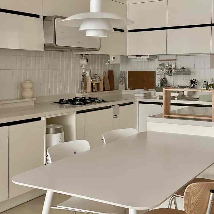 柔らかなホワイトとナチュラルウッドトーンが調和したシンプルな6畳のキッチン、中央に配されたダイニングテーブルと椅子が特徴的な清潔感のあるインテリア