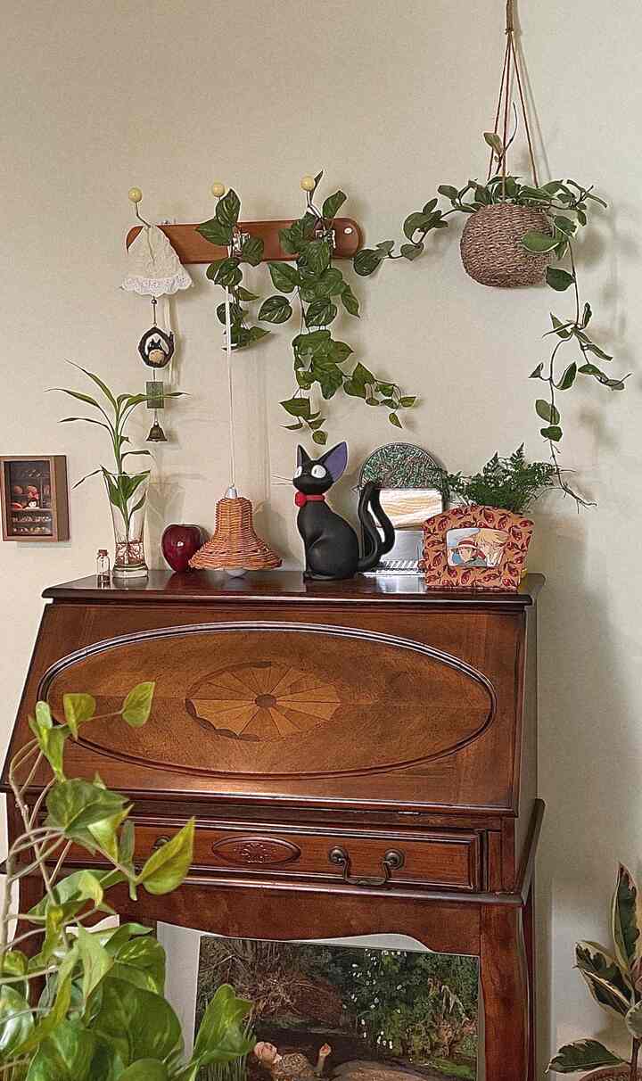 Natural wood tone vintage furniture and cat objet with plants decorate a charming bedroom space