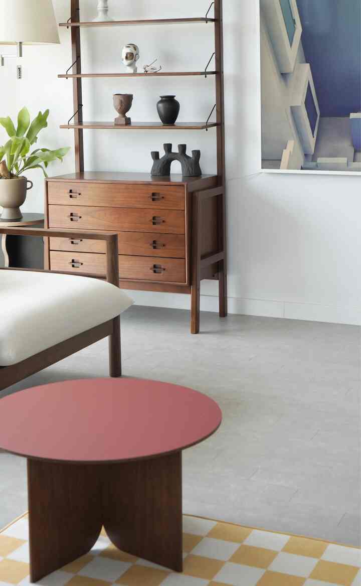 A simple living room featuring wood tones and gray flooring, with a coffee table and cabinet arranged neatly