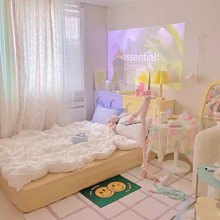 パステルカラーと白を基調とした寝室、かわいいバスマットと柔らかい寝具が配置された雰囲気のあるインテリア