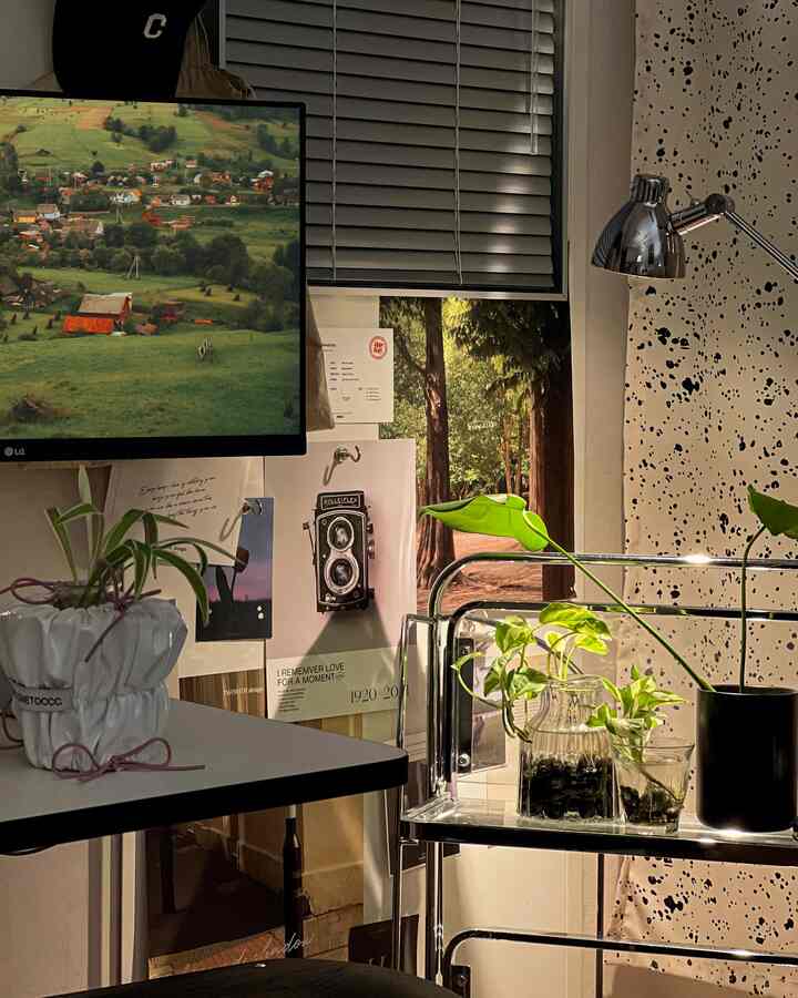 グレーのブラインドとポスターが配置されたホームオフィス、グリーンプラントがアクセントの温かみのあるインテリア