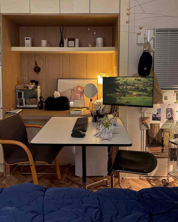 Natural wood tone wall and navy bedding in a compact home office space featuring desk and monitor creating a focused work environment