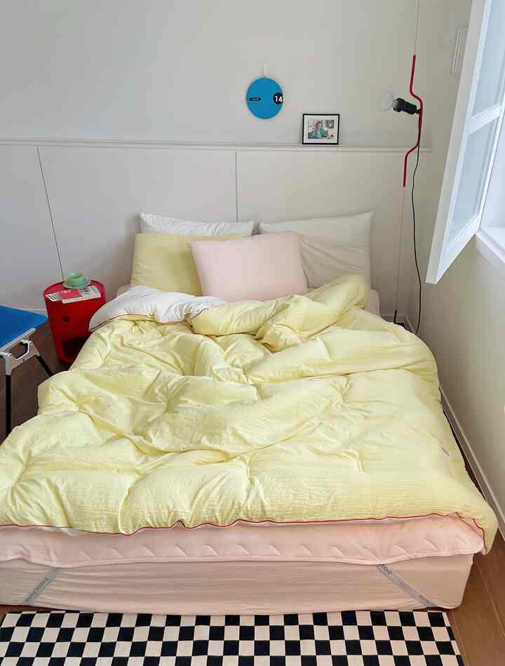 Pastel pink and yellow bedroom featuring a cozy bed with pillows centrally arranged in a comfortable space