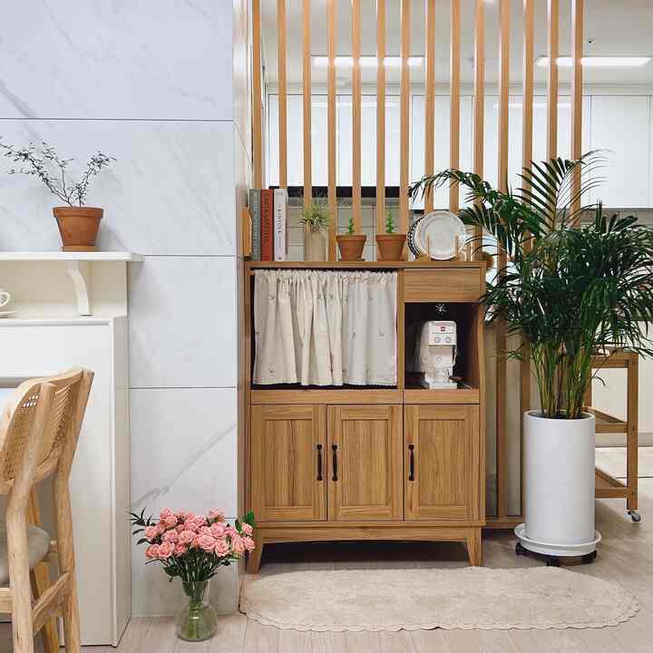 A natural and cozy living room with wood tones and white, featuring areca palm and various plants