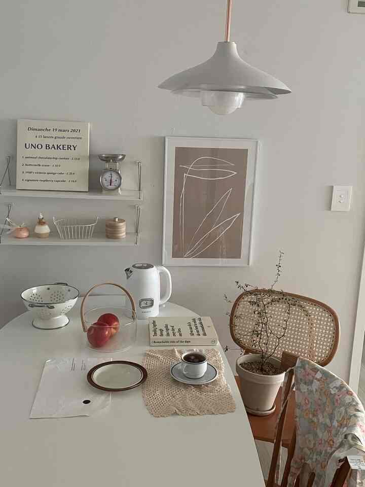 ベージュと白を基調としたダイニング、ダイニングテーブルとラタンチェア、カップと皿が配置された雰囲気のある空間