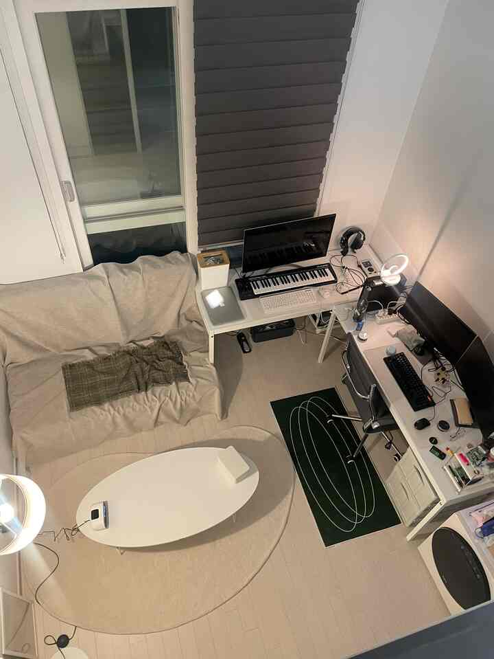 ベージュトーンのワンルームにデスクとソファが配置された音楽制作スペースと在宅勤務用ホームオフィス