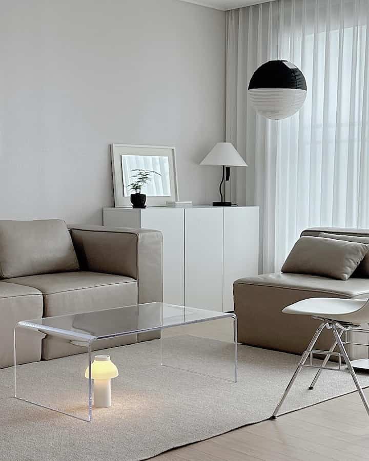 Beige and white tone living room featuring leather sofas and transparent acrylic table with a simple modern atmosphere