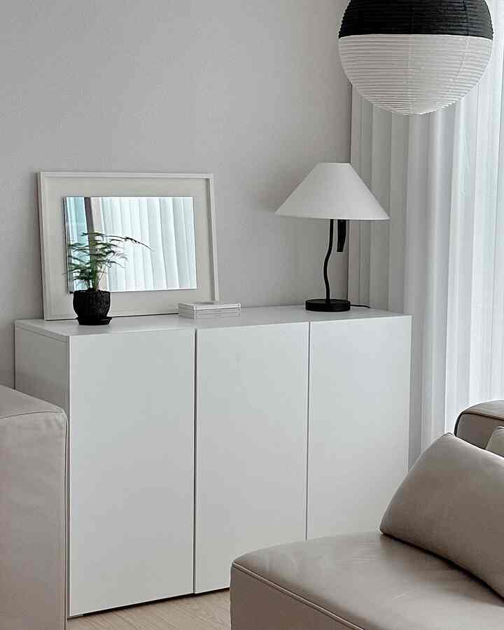 White and beige toned living room featuring a simple storage cabinet and lamp in a clean minimalist space