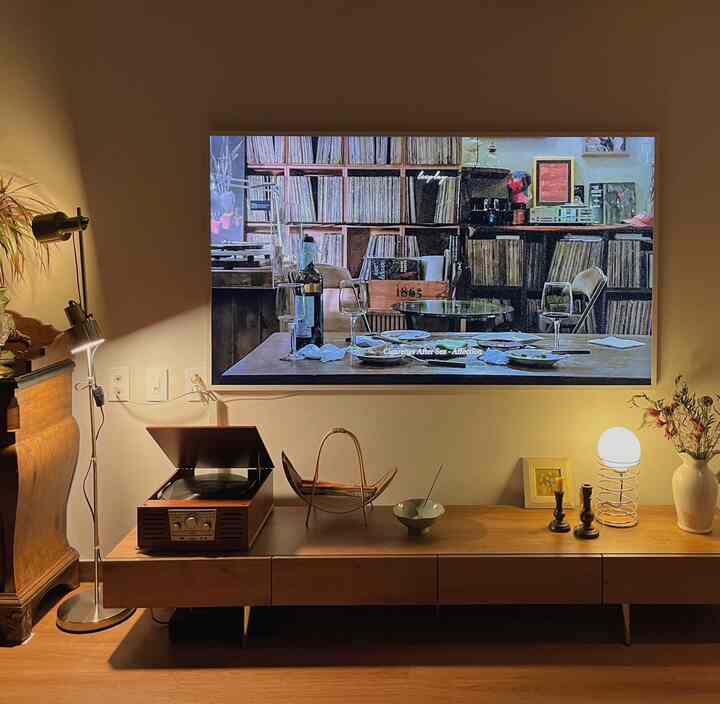 温かみのあるブラウン色調のリビング、壁掛けテレビとヴィンテージのメディアコンソール、柔らかな照明がある雰囲気のある空間