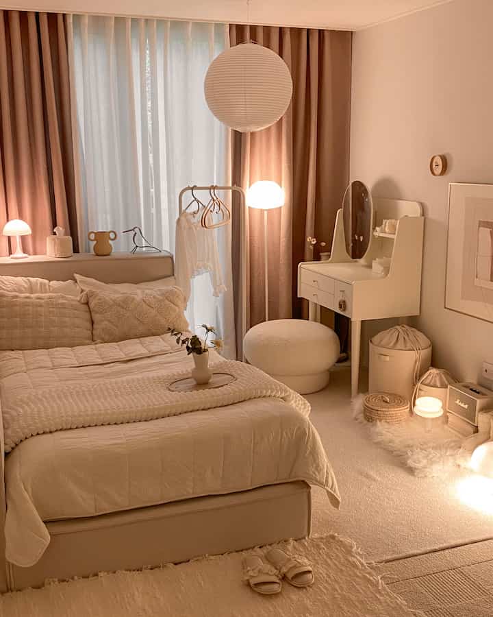 Beige and white toned bedroom featuring a bed, vanity, and indirect lighting creating a warm ambiance
