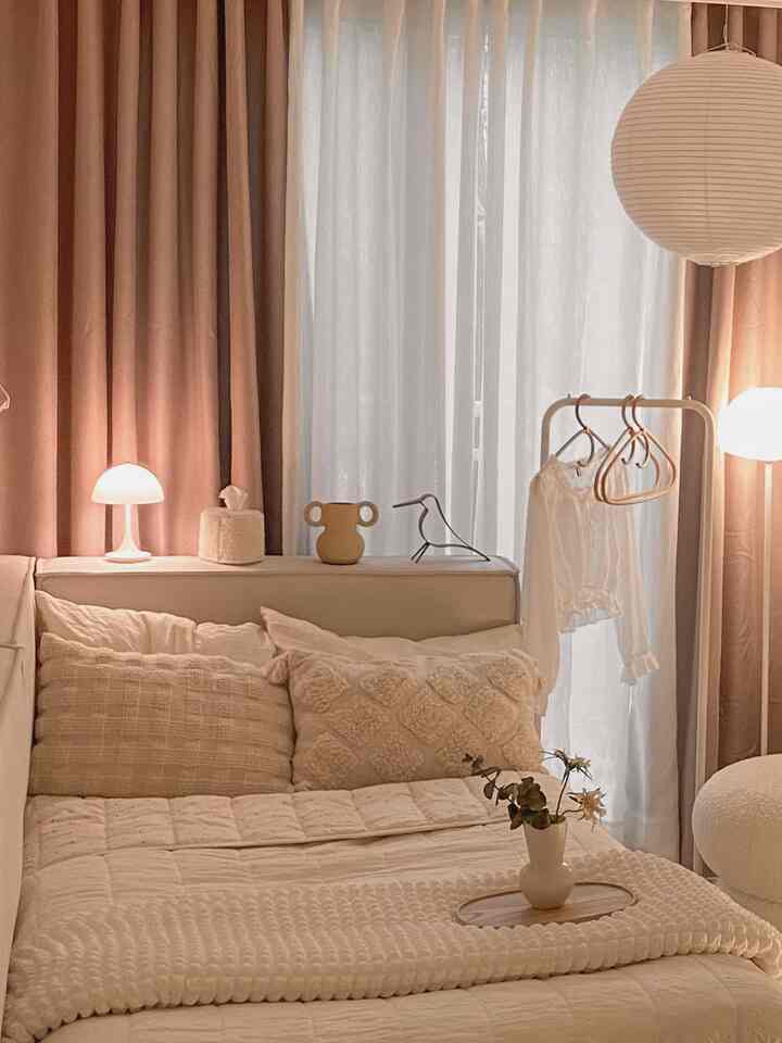 Warm beige and white bedroom with beige curtains and cozy sofa bed arranged in a snug space