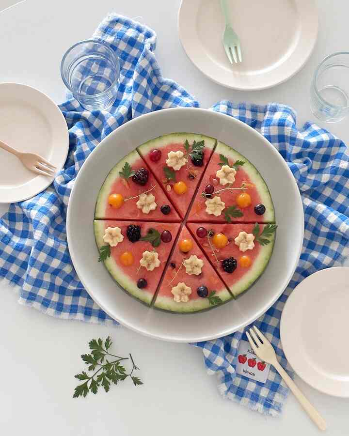 Bright and clean home party setup with blue check cloth and plated watermelon slices on a white table