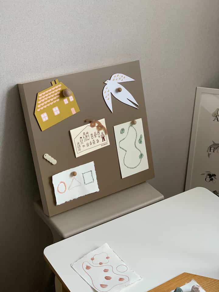 Natural toned kids' room featuring brown magnet board and clean white desk with simple decor
