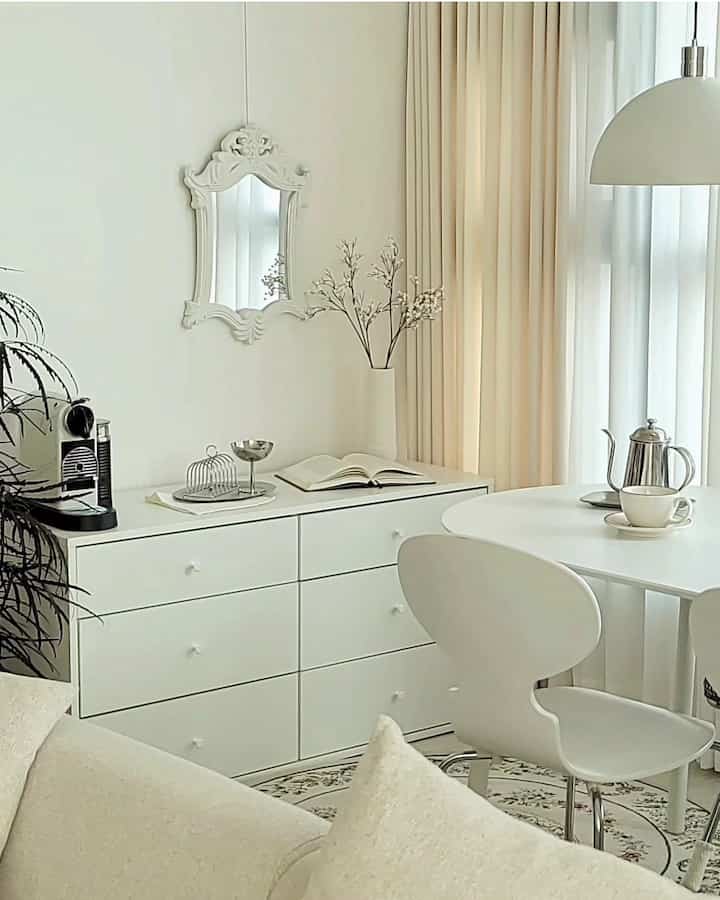 Bright white-toned dining room featuring a central 6-drawer dresser and simple dining chair in a clean minimalistic setting