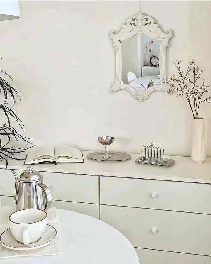 White-toned space featuring a 6-drawer dresser, white framed mirror, and home cafe accessories in a minimal and simple setting
