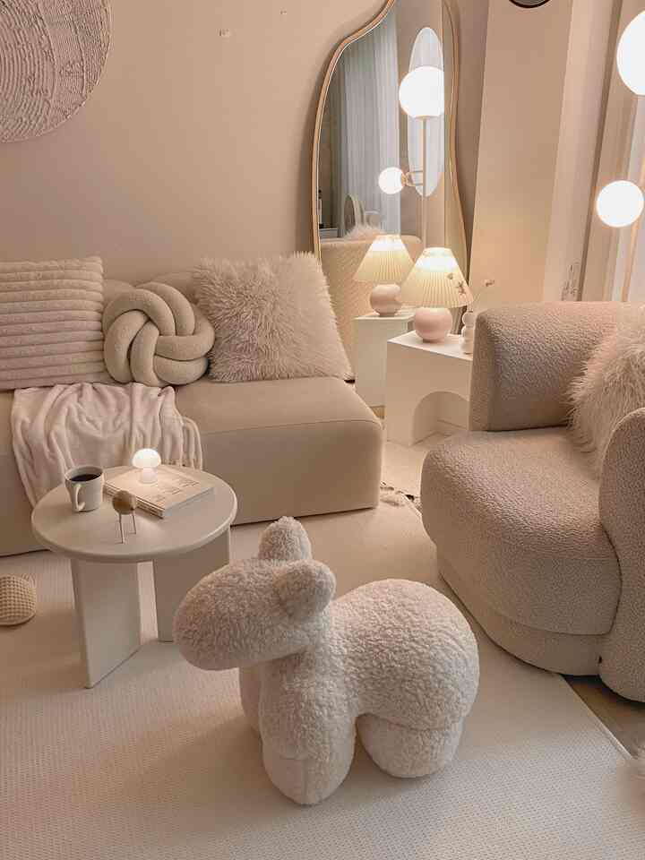 Beige-toned living room featuring soft-textured sofas, curved mirror, and floor lamp with a simple and natural atmosphere