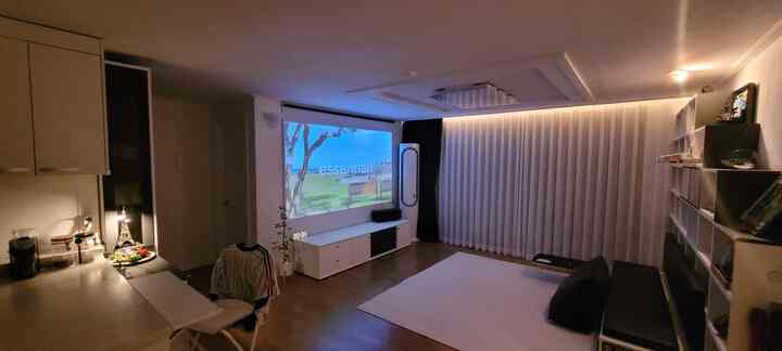 Minimal white-toned living room featuring a home cinema with projector screen and a cozy home cafe setup