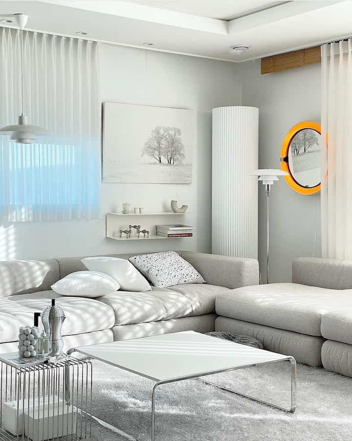 Bright light gray living room featuring a large sectional sofa and white coffee table with a simple modern ambiance