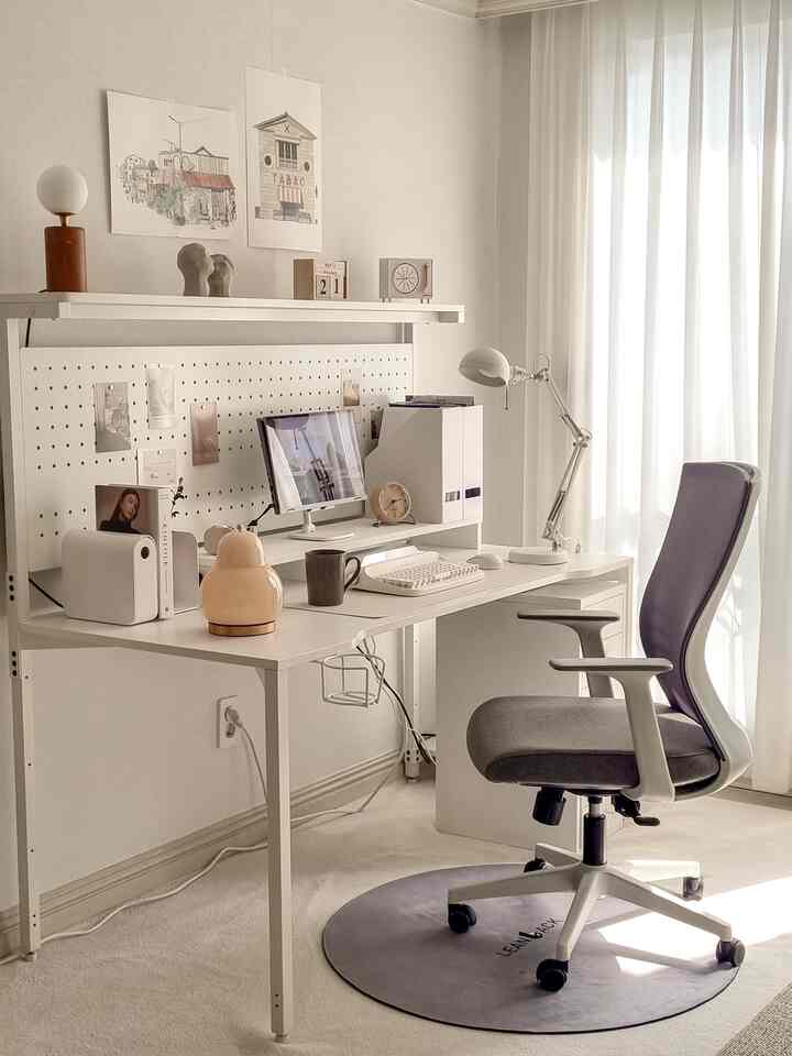 Bright white and gray-toned study space featuring a computer desk and office chair neatly arranged under natural light