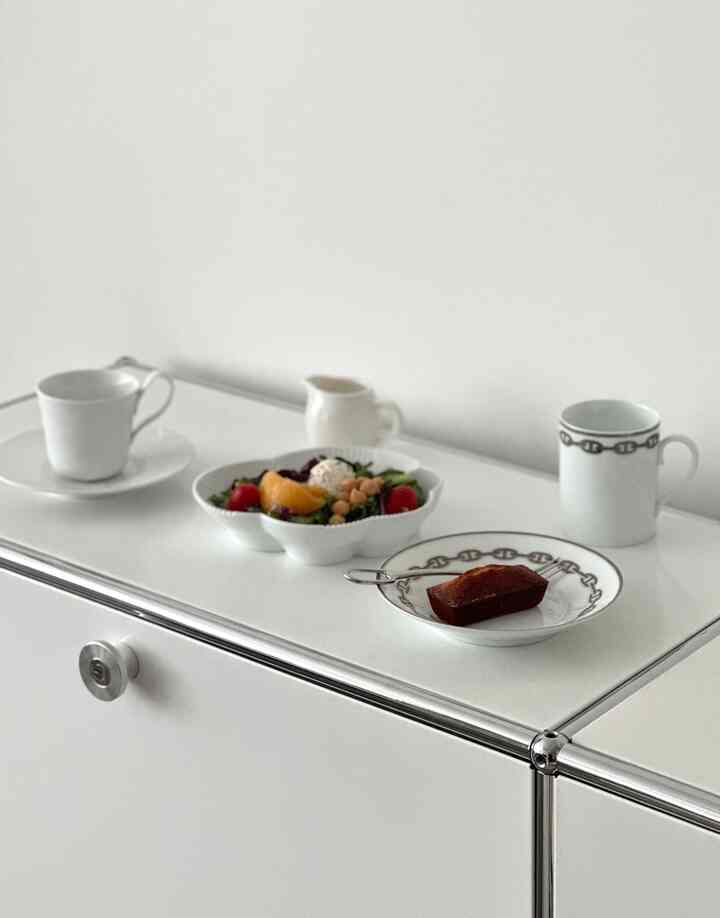 White-toned dining space featuring Royal Copenhagen White Elements line and Hermès mugs with a simple, elegant table setting