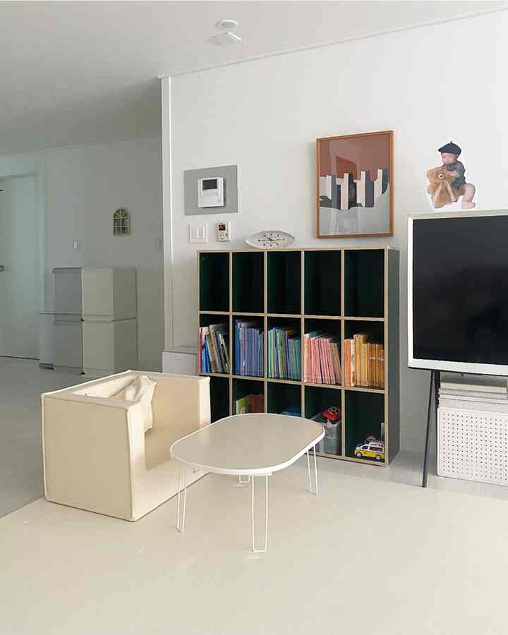 ホワイトとベージュのトーンの小さな子供部屋、子供用家具と本棚が配置されたミニマルなインテリア