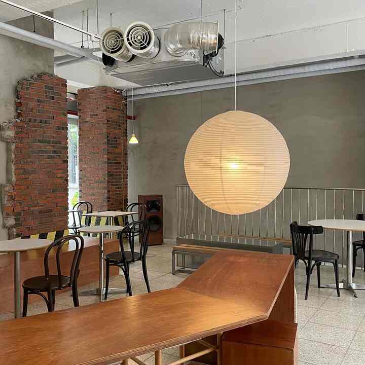 Warm brown and gray toned cafe-style interior featuring round pendant light and wooden furniture in cozy space