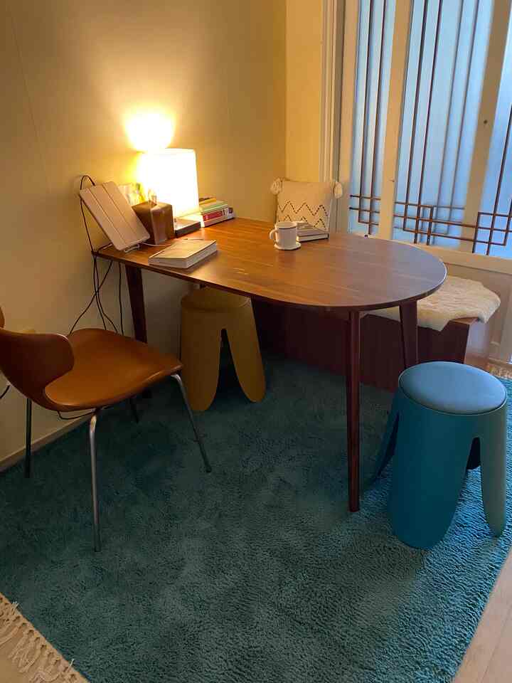 暖かいブラウンとブルーのトーンのダイニングルーム、木製のテーブルと多様な色の椅子が配置された雰囲気のあるインテリア