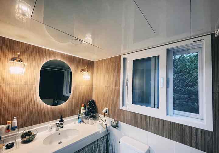 Brown and white toned bathroom featuring central mirror and wall sconces with a clean atmosphere