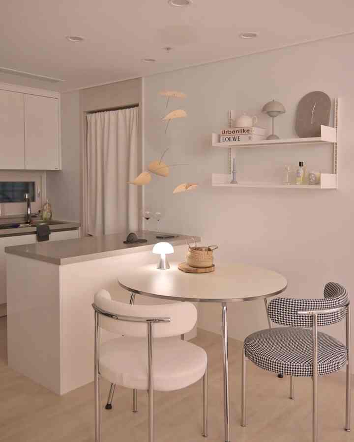 ホワイトとナチュラルトーンのキッチン、丸いダイニングテーブルと棚が配置されたシンプルでモダンな印象的な空間