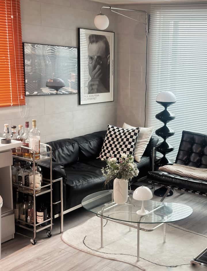 Monotone black living room featuring a black leather sofa and transparent glass table with a modern, clean atmosphere