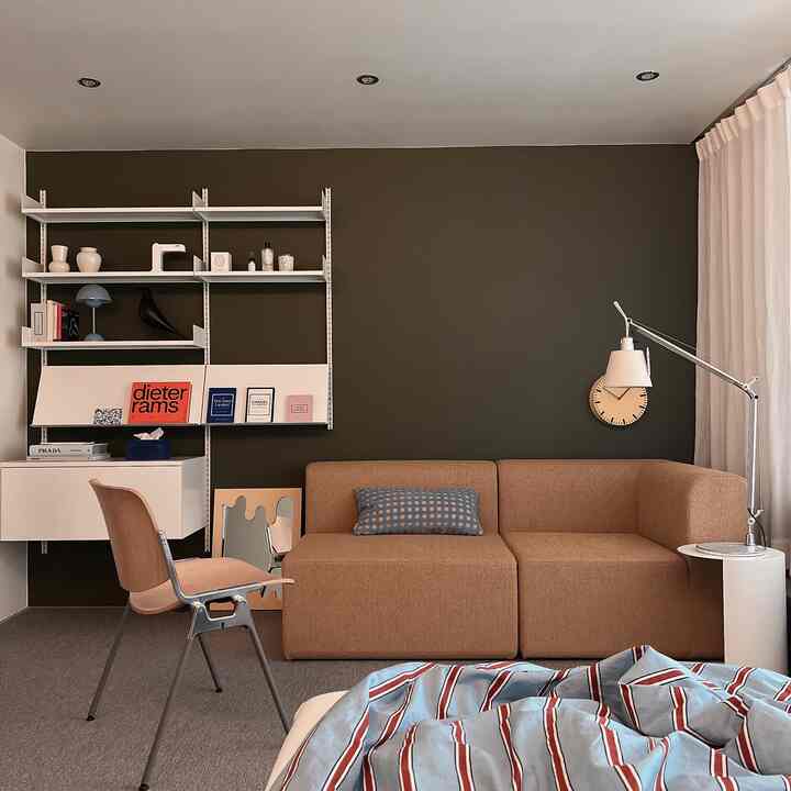 Modern living-bedroom space with a green accent wall and beige sofa