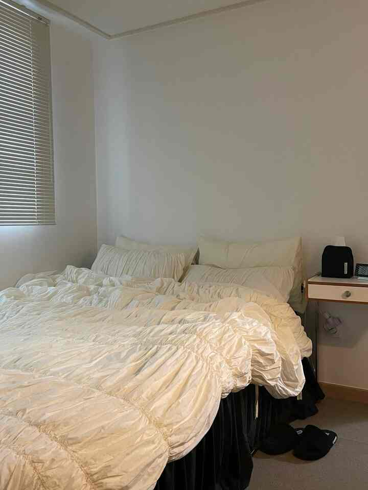 白と黒のトーンの寝室、白い寝具とナイトテーブルが配置された清潔感のある空間