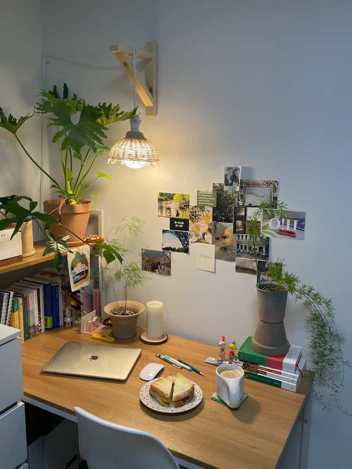 Natural wood-toned small studio room desk space featuring plants and home cafe elements, creating a cozy and inviting atmosphere