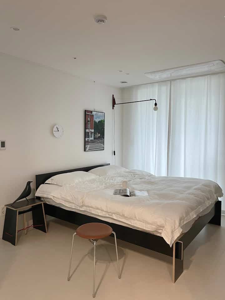 White-toned bedroom featuring Moormann bed, white duvet cover, and curtains in a modern and simple style space