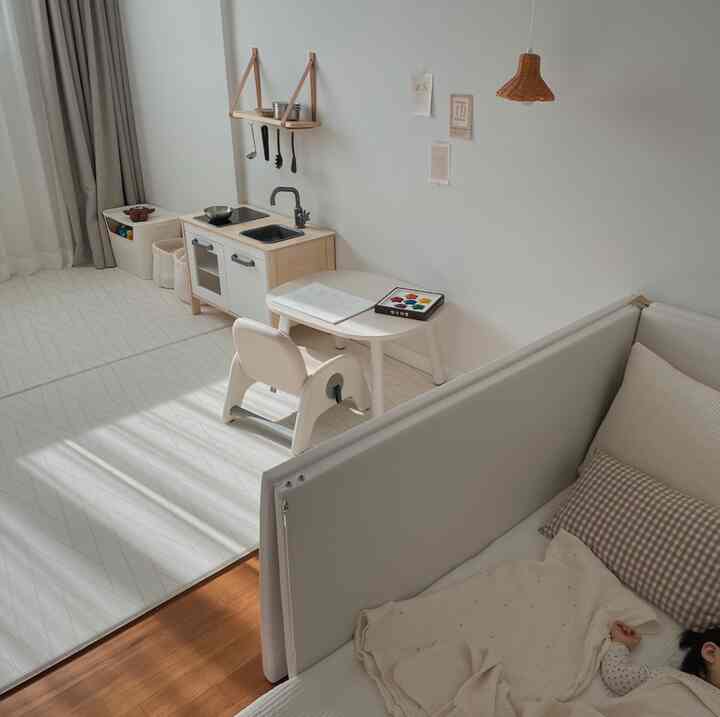 A spacious kids' room in natural tones featuring a play kitchen and children's desk set in a cozy layout