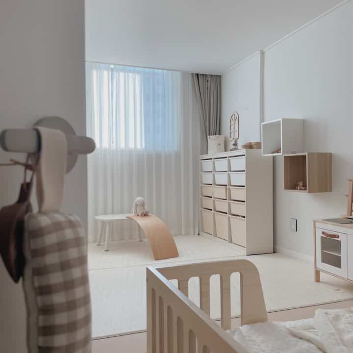 白とナチュラルカラーが調和する赤ちゃん部屋、ベッドと収納が整った印象的な空間